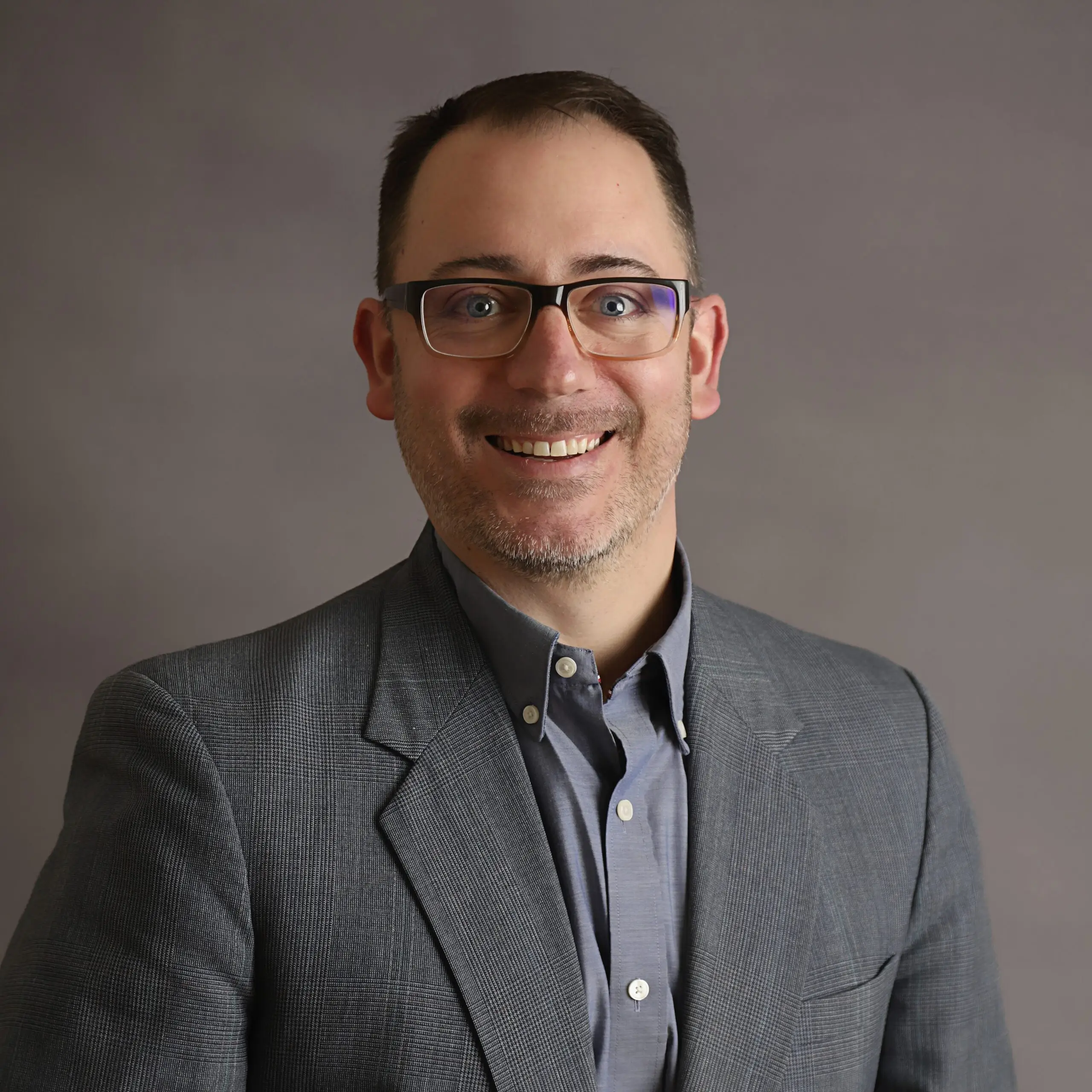 Smiling man in suit and glasses.