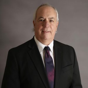 Smiling man in a black suit and tie.