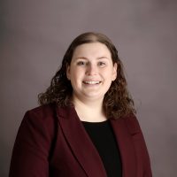 Person in maroon blazer smiling confidently.